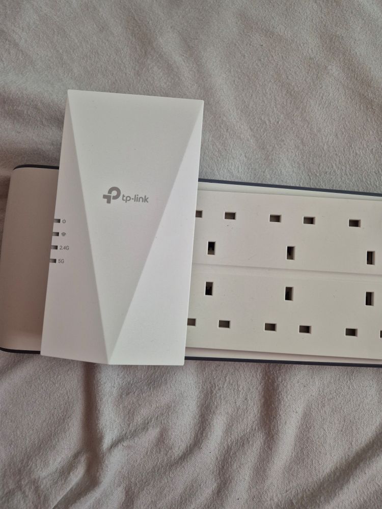 a tp-link range extender that I'm using as a wifi bridge, plugged into a double row power strip. the range extender is a single unit with an integrated plug, and it's so big it blocks three extra sockets when it's plugged in