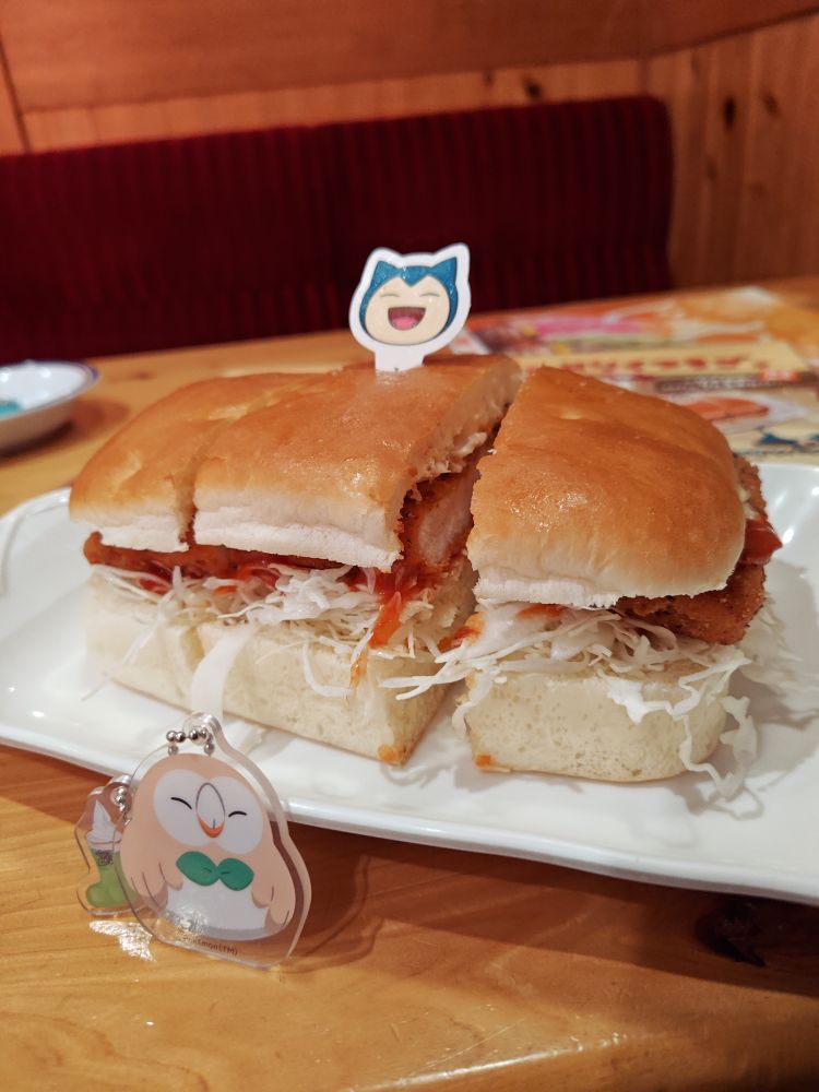 コメダ珈琲店のポケモンコラボ商品、カビゴンのサルサチキンカツパンとおまけのアクリルキーチェーン（ランダム）です　おまけはモクローとメロンクリームソーダだった