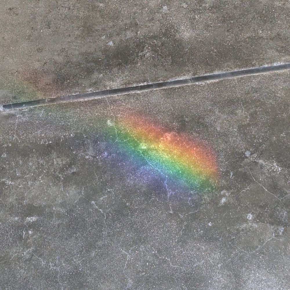 コンクリート製の床に虹色の光がさしている