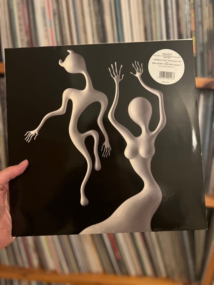 White faceless figures - a male with devils horns and a female wiggle on a black background