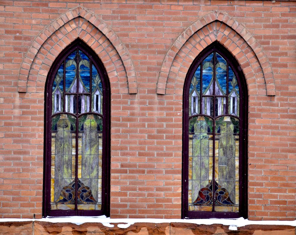 Old brick church with two stained glass windows. 