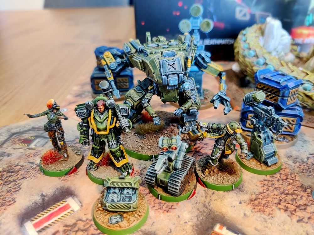 The Ariadna company/faction of Deathmatch: TAG Raid from Corvus Belli. A large, crab-like and fairly industrial looking TAG (mech), a smaller catterpillared drone, and three infantry. 

Painted in typical ariadnan green, with yellow accents.