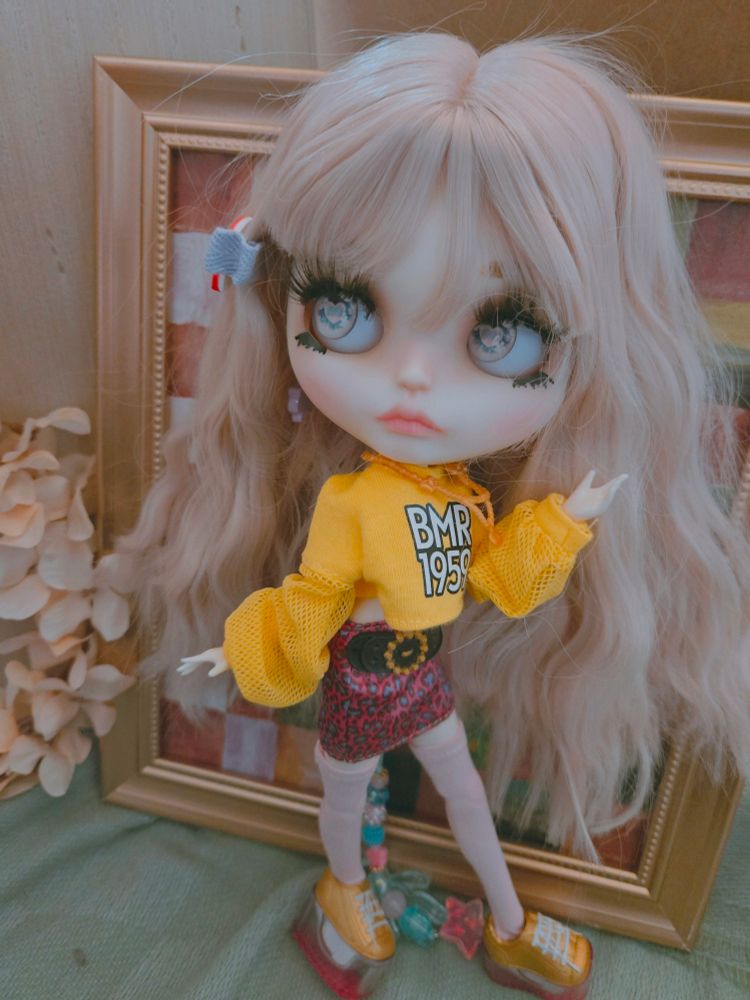 My doll Everleigh with crimped hair wearing a yellow sweater, pink mini skirt, and tall yellow sneakers