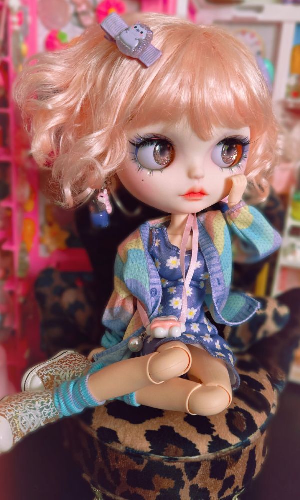The doll sitting with her cheek in her hand and looking thoughtfully to the right