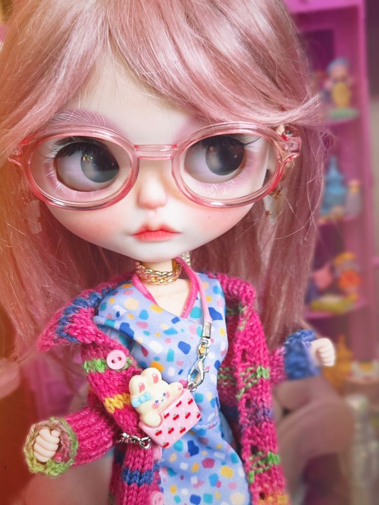 Big-headed Blythe doll with pink-purple hair and pink glasses. She's looking right with blue-grey eyes