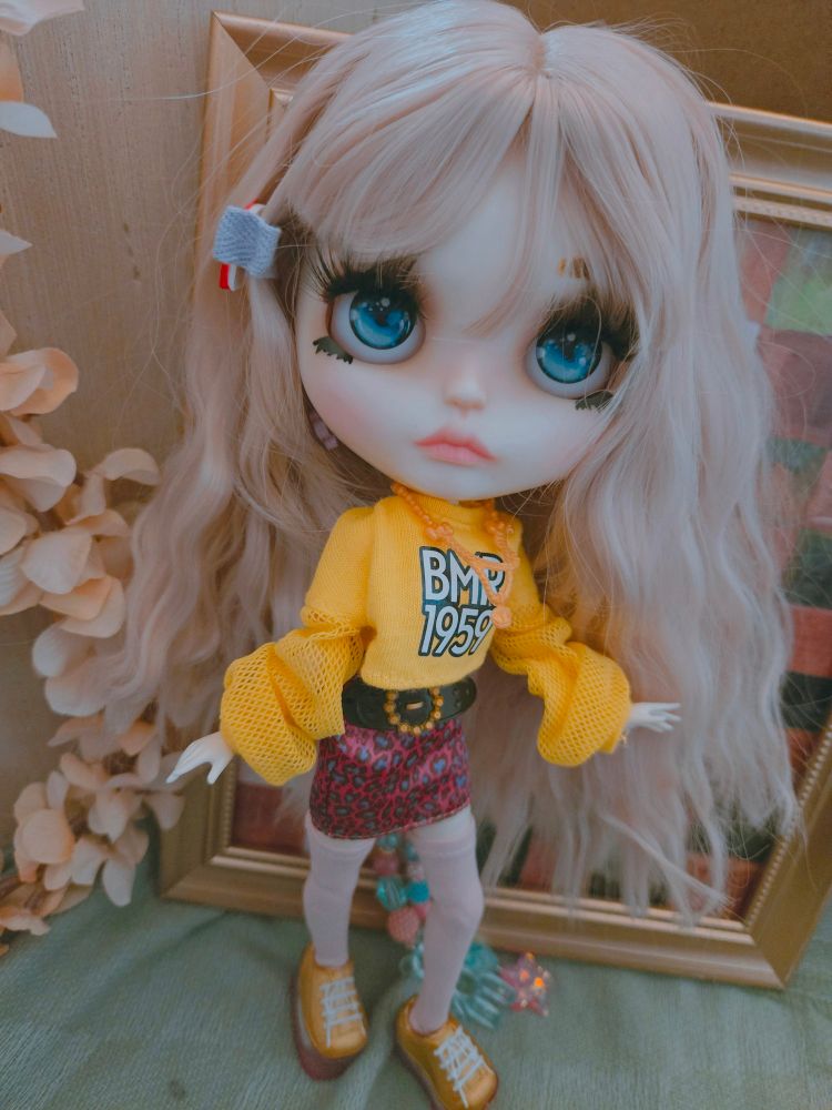 My doll Everleigh with crimped hair wearing a yellow sweater, pink mini skirt, and tall yellow sneakers