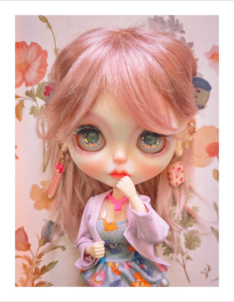 The doll looking upward with her hand by her mouth