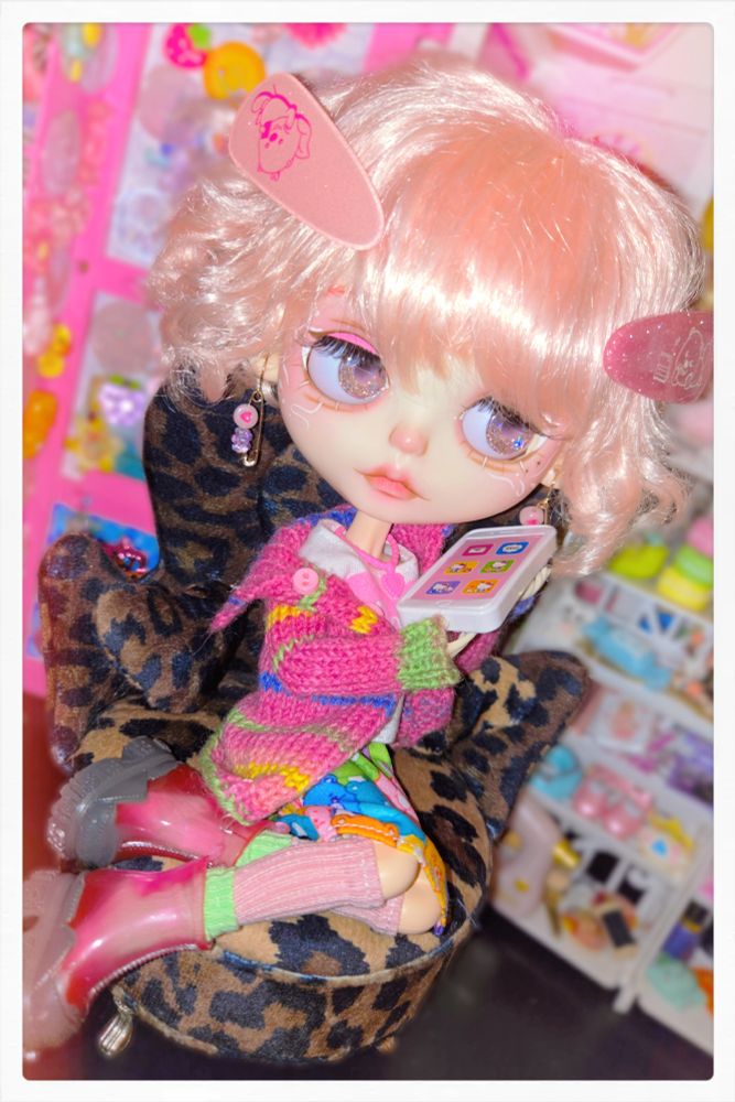 The doll holding the giant phone up to her ear to take a call