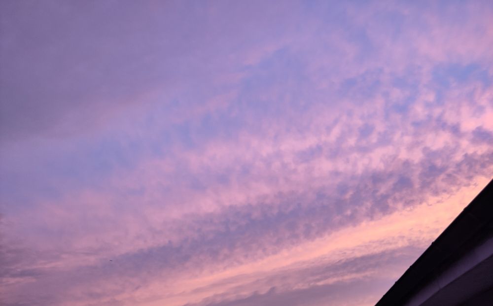 clouds forming streaks of blue, grey, and bright yellow-orange, with some darker altocumulus (?) bands