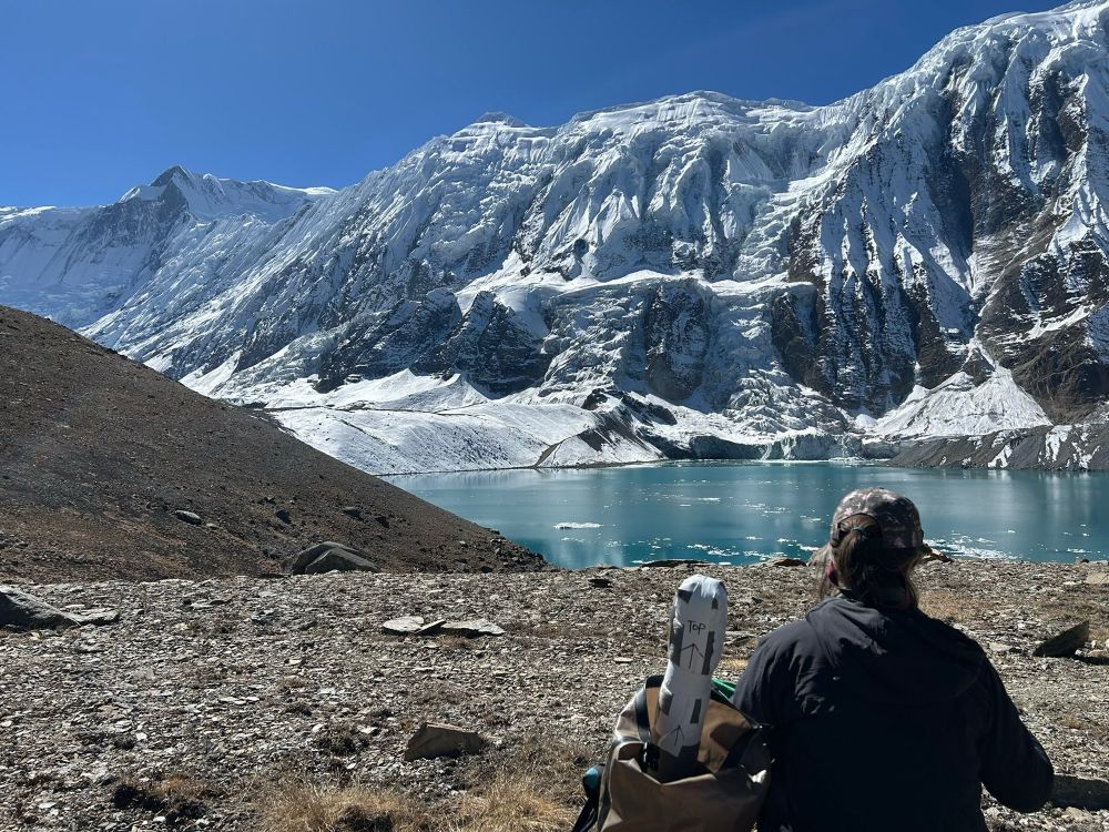 Lake Tilicio in the Annapurna Range at 4500 m altitude - picture shows a Bianca Perren carrying a core collected from the lake back down in her rucksack looking out across the lake and majestic mountain range 
