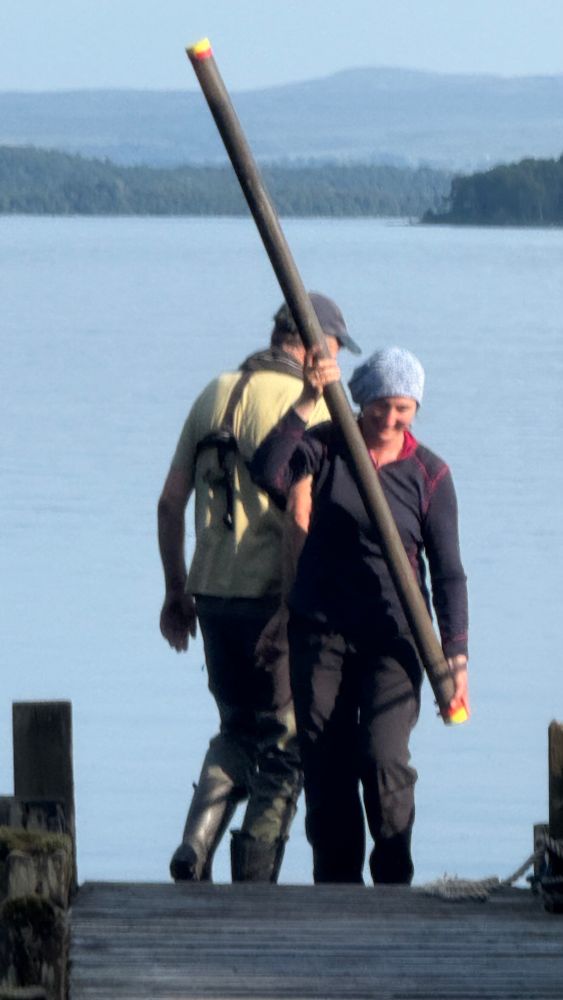 Ellen Tisdall carrying a core back to shore along the boat jetty at the end of days’ coring 