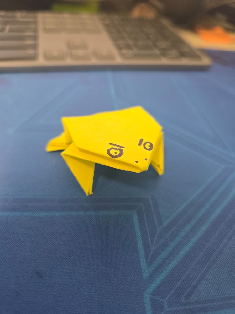 An origami frog with eyes drawn onto it