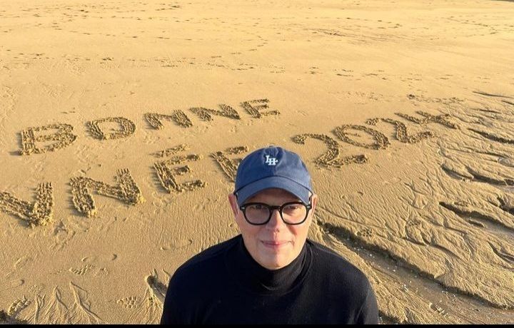 Edouard Philippe, avec une casquette sur la plage, avec écrit dans le sable "Bonne année 2024"