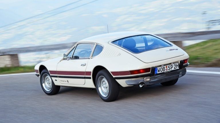 Volkswagen SP-2, vue de derrière, dans un virage à gauche. La voiture est blanche, une bande de couleur bordeaux ceinture la caisse dans le prolongement des feux