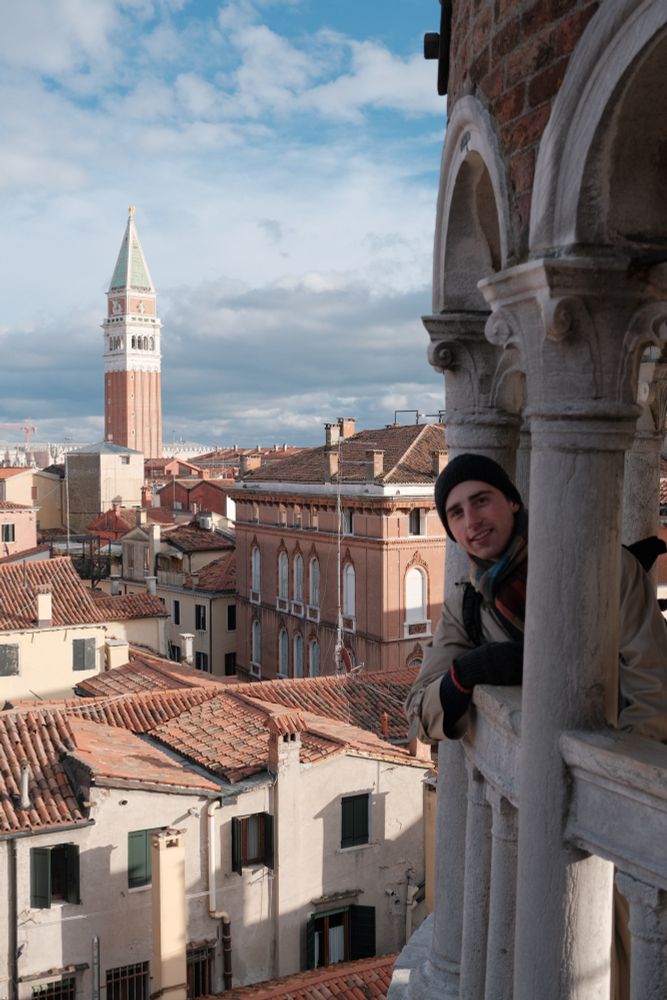 In an open air tower peering out with the bell tower from San Marco square in the background