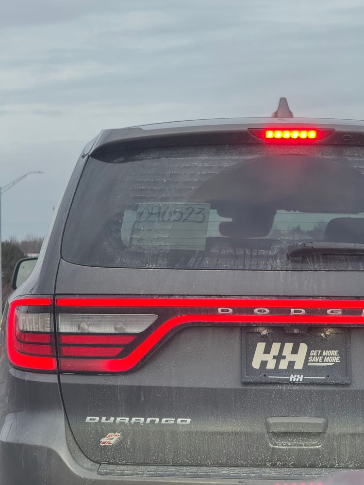 The rear of a black Dodge Durango with no license plate and an in-transit tags in the rear window dated 04-05-2023.