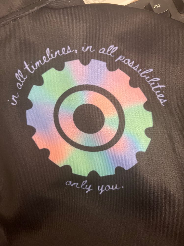 close up of the pastel gear design with the text “in all timelines, in all possibilities, only you” 