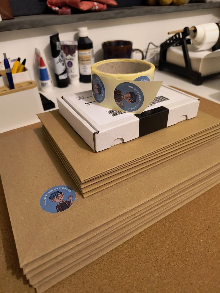 A big stack of envelopes and one small box, with a roll of custom stickers placed on top to obscure the address on the shipping label.