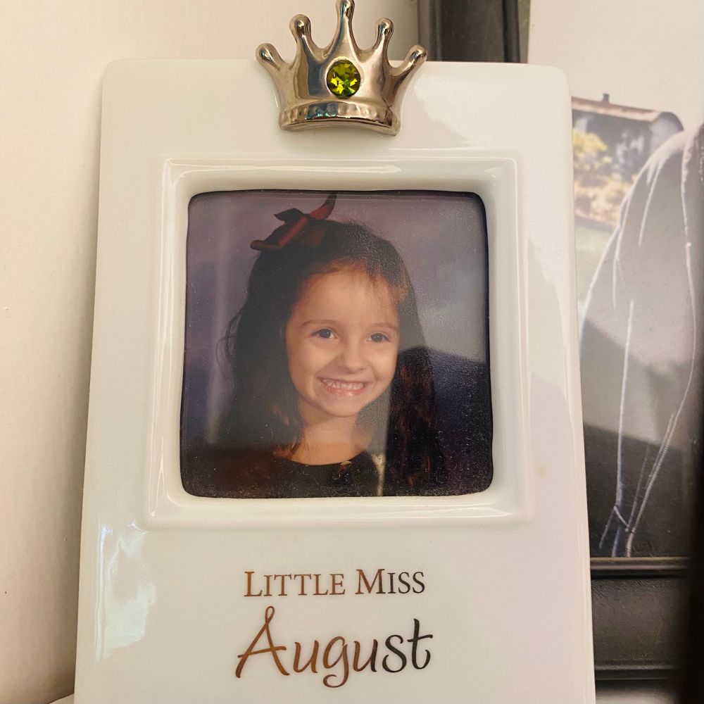 a framed photo of when I was a little girl. the frame says “little miss August”