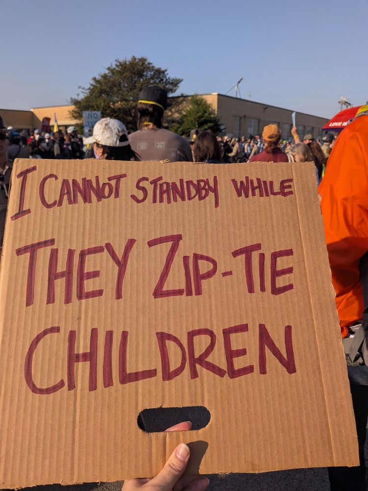 a cardboard sign at the Broadview facility protest reads I cannot standby while they zip-tie children 