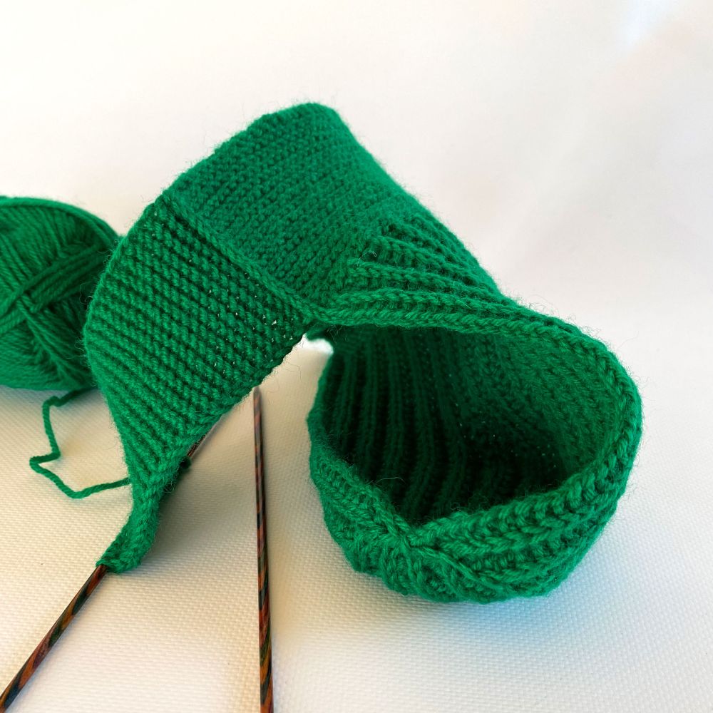 An Ammo Jockstrap in kelly green yarn being knit. This medium size pouch is finished, and the waistband is underway.