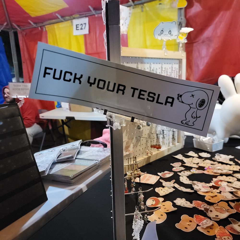 Sticker that says, "Fuck your tesla" and has a snoopy smoking 