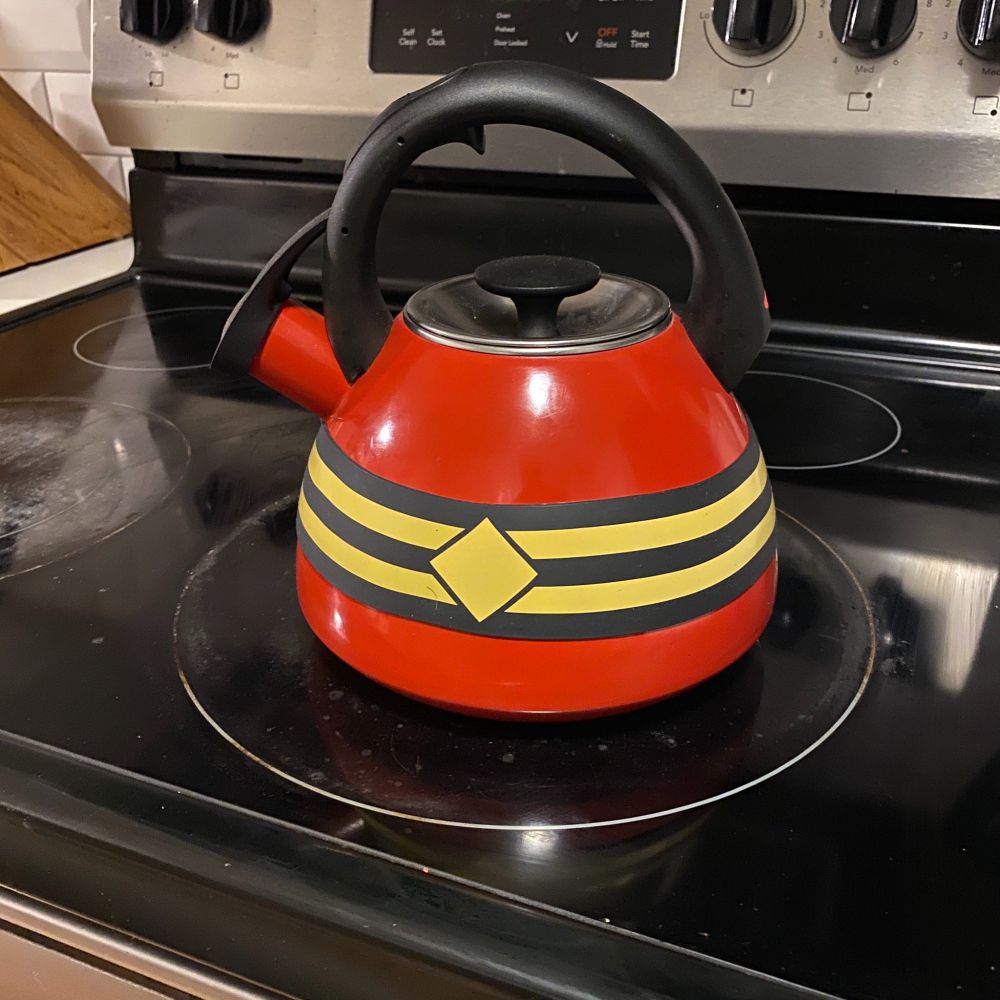A red teakettle with the Plastic Man band around the middle 