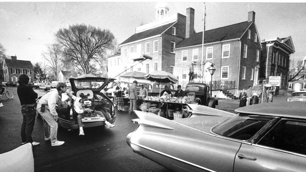 Film crews work from the back of a car as they shoot a scene in New Castle for the movie "Dead Poets Society". Old cars lined the street for the scene. 11/16/88
Photo By Chuck McGowen