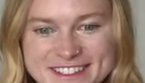 Estatico de uma mulher loira sorrindo com a cara meio travado e olhando pro nada