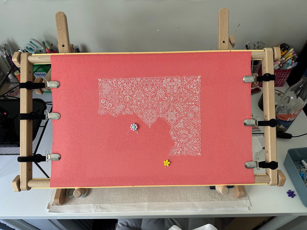 Zoomed out photo showing the cross stitch piece on the scroll frame 