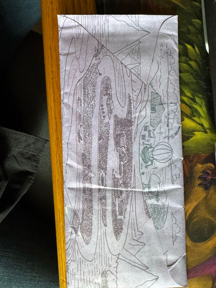 Purple envelope with a landscape drawing featuring a camp site and a hot air balloon 