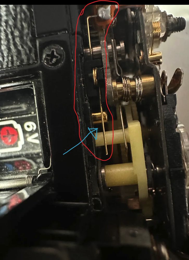 This is a picutre of what's under the left hand side of the Canon AE-1 Program's top plate.

Circled in red is a small golden spring (probably plated). This spring want to contact a golden (also probably plated) post.

I drew a blue arrow pointing to the contact point that can get dirty.

Normally after you advance the camera, the white plastic bit at the end of the sprint moves out of the way, the tension on the mechanism makes this contact act as a closed switch. Camera uses this switch to both know that the shutter is ready to fire, and the fact that the 1st curtain started moving (for exposure time control)