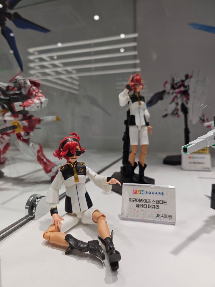 <수성의 마녀> 에 등장하는 '슬레타' 피규어
선글라스를 끼고 거만하게 웃으며 앉아있다.