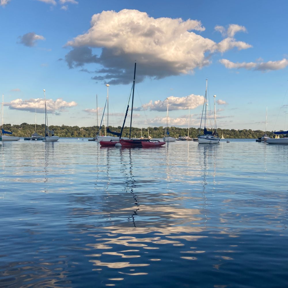 Lake Harriet at sunset. Big cloud at the top of the picture reflected in the rippling water. Buncha sailboats in the foreground