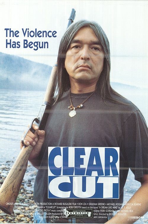 Graham Greene in Clear Cut, a 1991 Canadian folk horror thriller. Greene carries a rifle on his shoulder and is standing at the edge of a large lake, hills and mist visible behind him. There's a slogan, 'the violence has begun', and the title 'Clear  Cut' is displayed. 