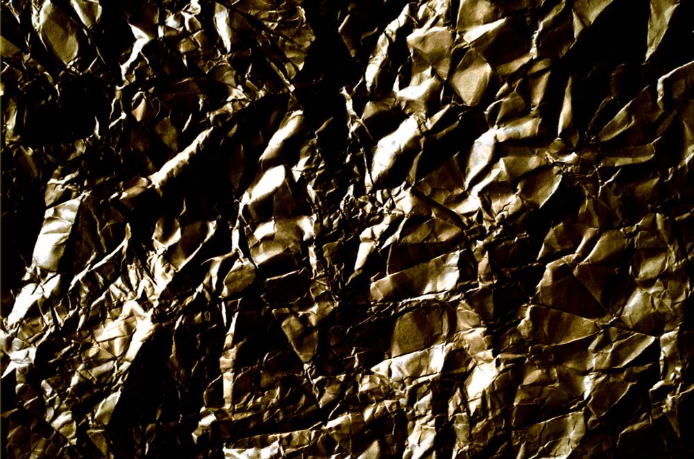 Abstract image. White and gold over a backdrop of crumbled black. 

Image created by the author.