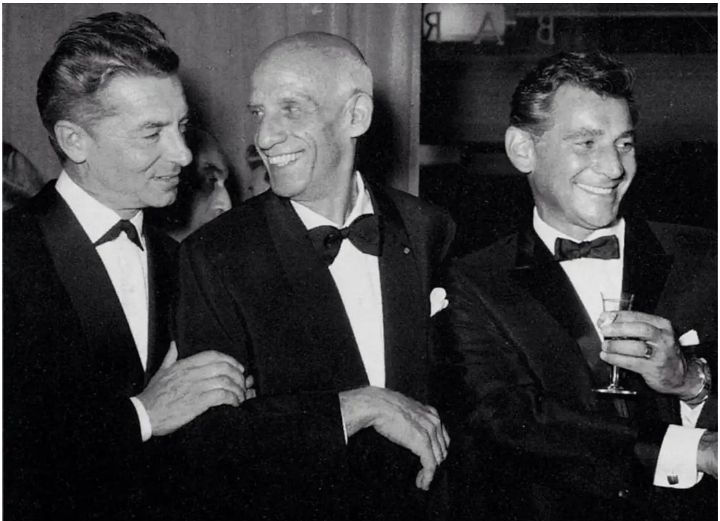 Maestros Herbert von Karajan, Dimitri Mitropoulos e Leonard Bernstein em pé e vestidos a rigor em alguma solenidade não indicada. Foto em preto e branco.
