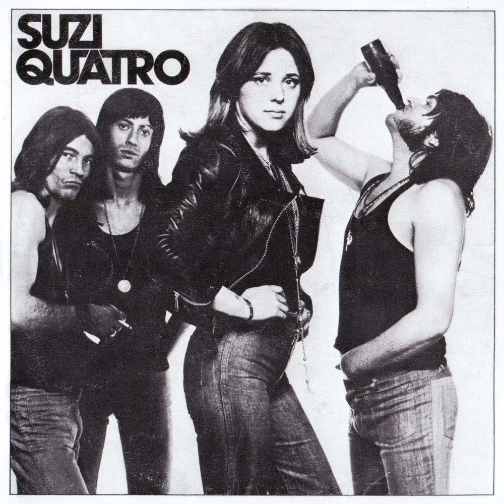Cover von Suzi Quatros erster Platte. Suzi im Vordergrund, ihre Band im Hintergrund. Schwarzweiß, alle im Denim-Look, einer trinkt Bier, einer hält eine Kippe.