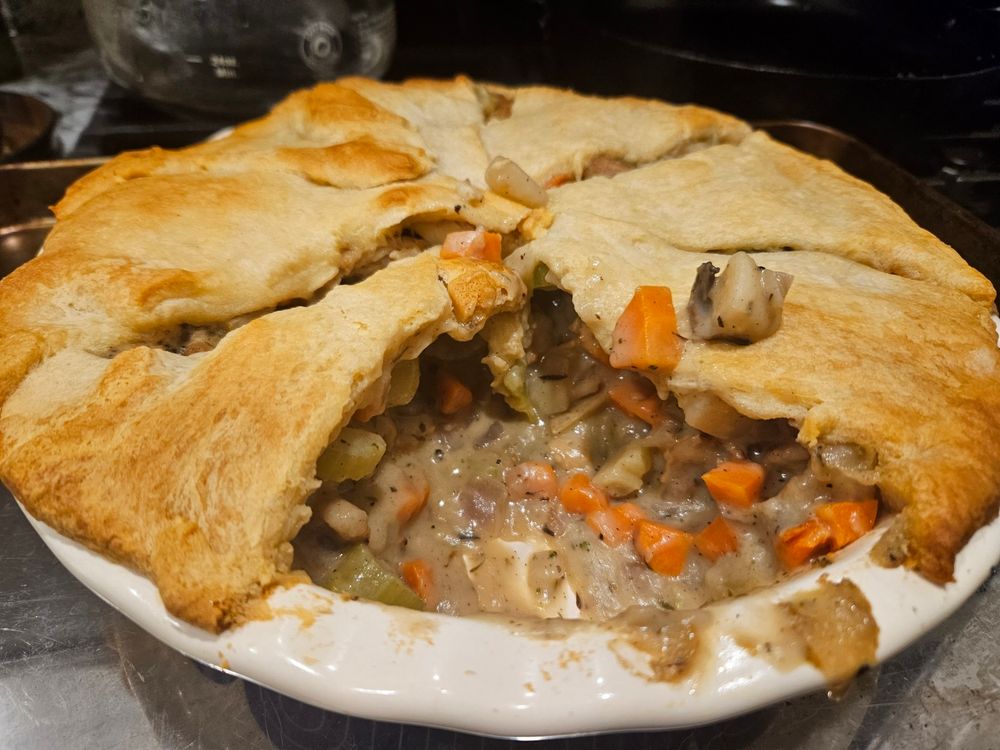 a vegan chick'un and vegetable pot pie with a slice cut out of the pie pan