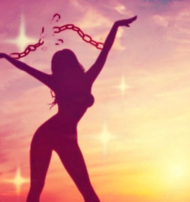 Silhouette of a gorgeous woman breaking free from chains around her wrists in front of a sparkling sunset, feeding between pink yellow and orange.
