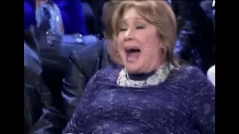 a woman in a blue dress is laughing with her mouth open in a crowd .
