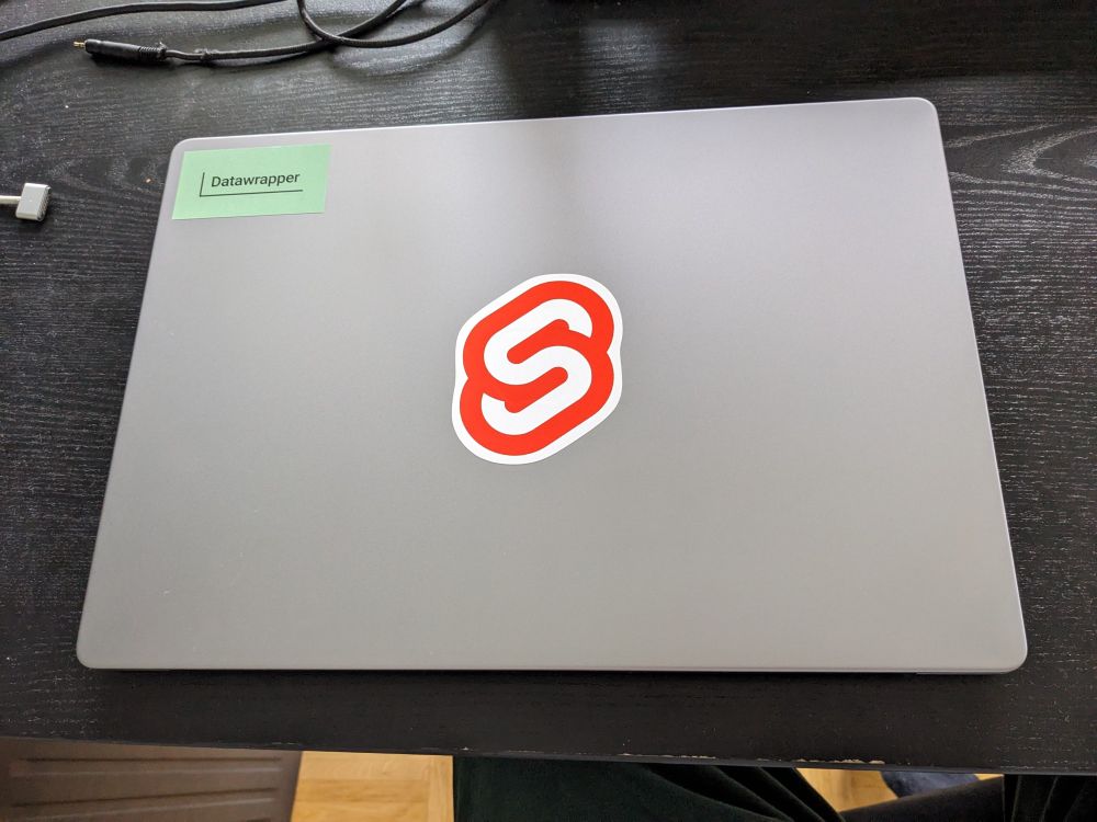 my new work MacBook Pro 16in with Svelte sticker over the Apple logo and a Datawrapper in the top left corner