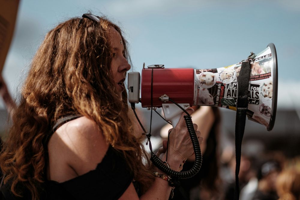 Woman and megaphone emblazoned with animal-rights stickers. Photo by Clem Onojeghuo on Unsplash