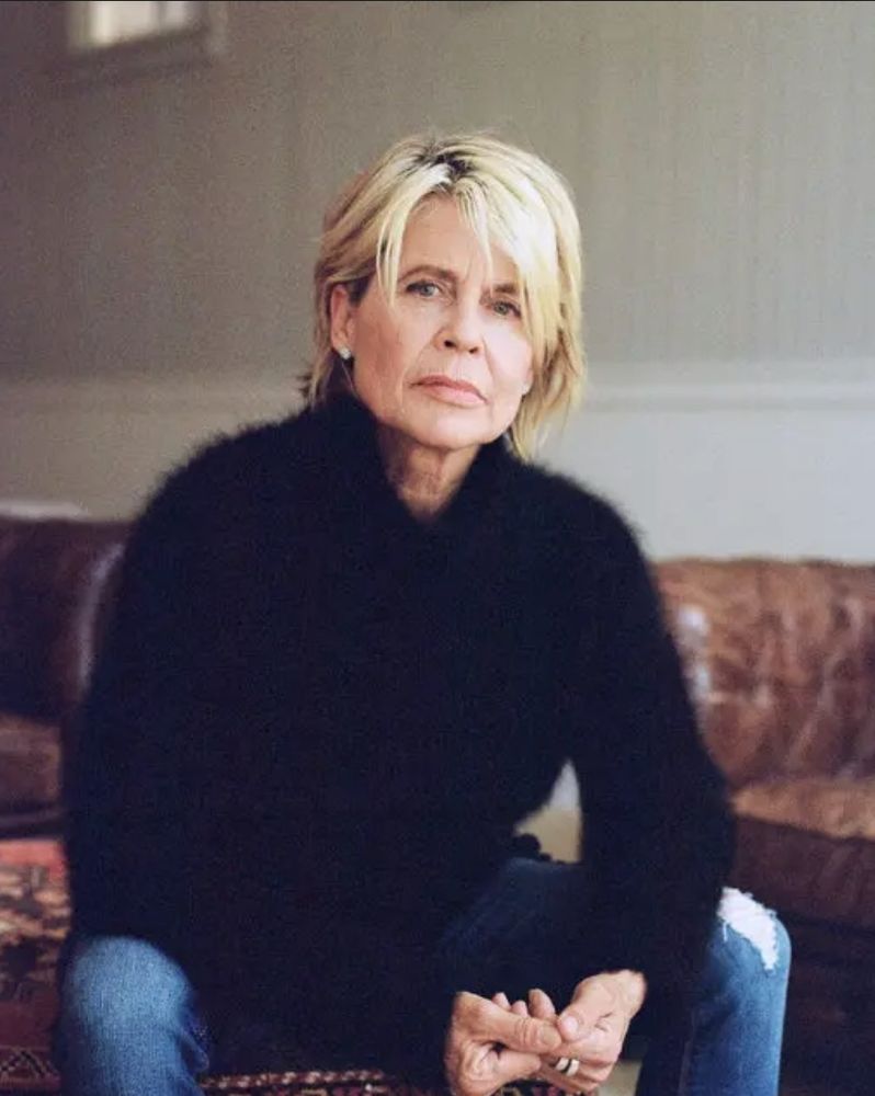 Linda Hamilton in a 2019 photo with chin length blonde hair, steely blue eyes and a fuzzy black sweater