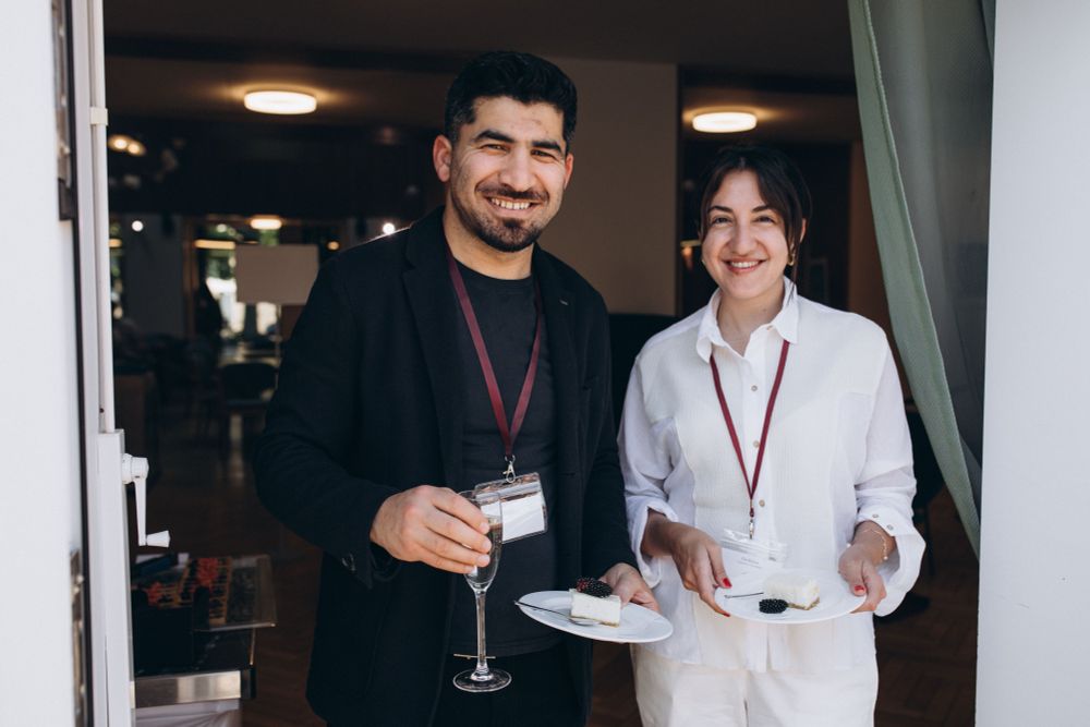 Two historians wearing lanyards and holding plates and glasses