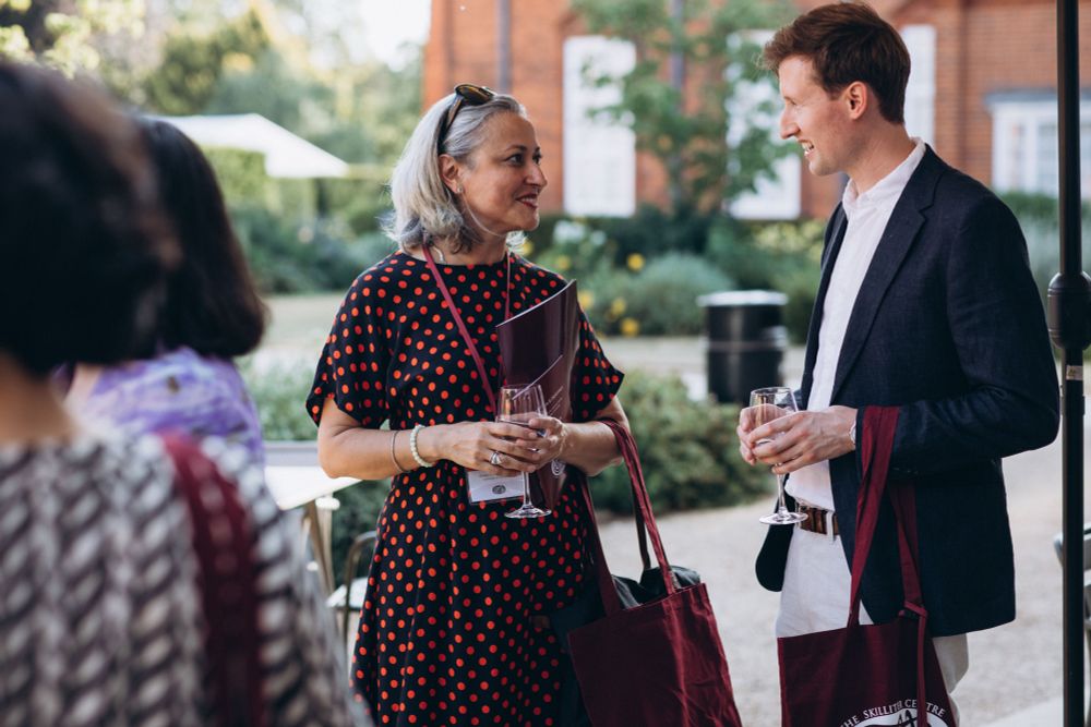 Two historians talking in Newnham College garden, with others in the background