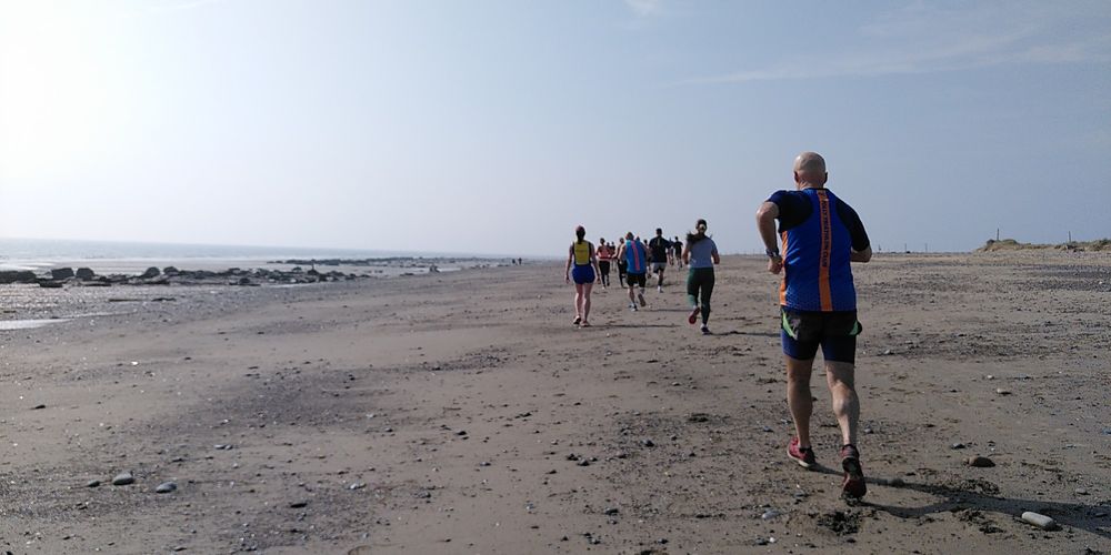 The long stretch of sand at Spurn point, water the the left, and a line of runners ahead, all dashing to the lighthouse and back, for the Spurn 7 mile race, 'cos it's there