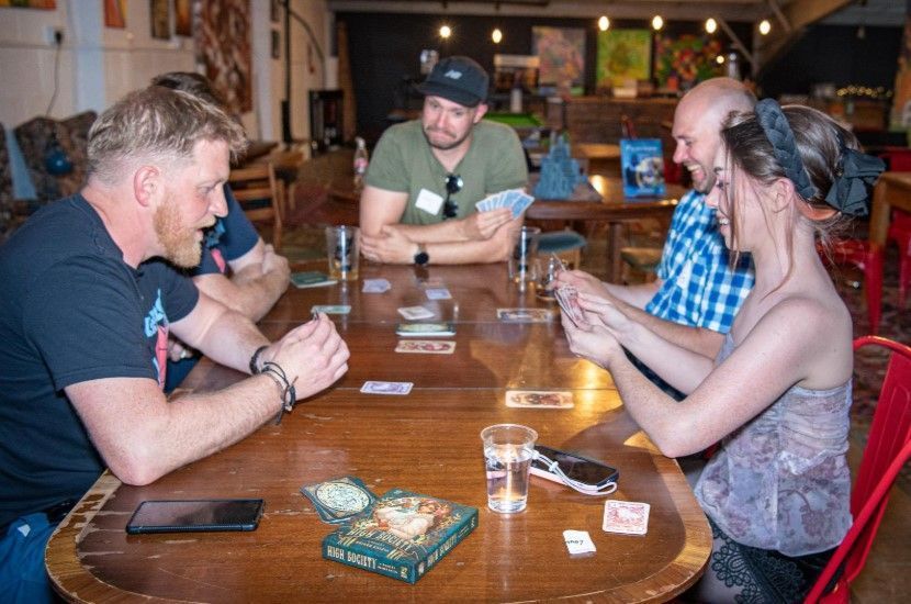 A photo of people sat around a table playing the card game High Society.