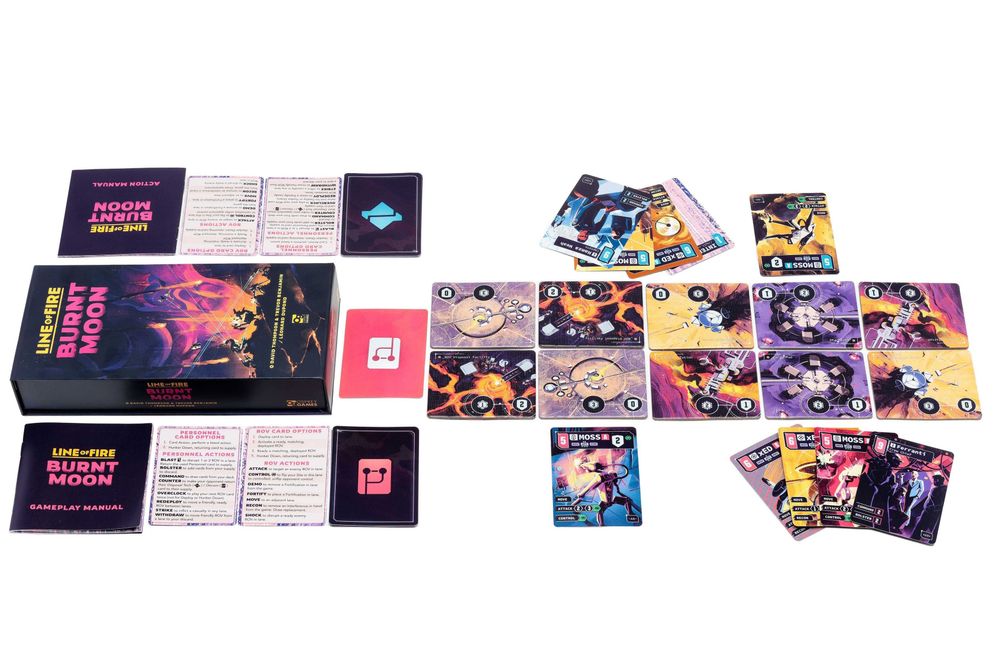 A photo of the game box for Line of Fire: Burnt Moon alongside two rulebooks, reference cards, and decks of illustrated cards next to illustrated punchboard terrain tiles.