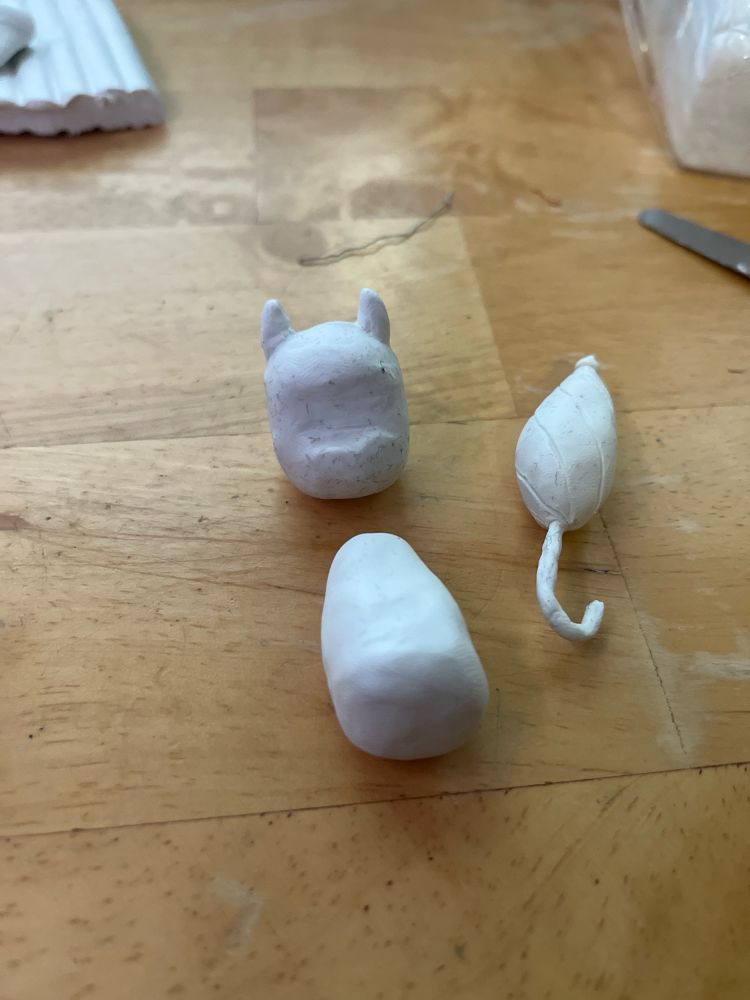 The head, body, and umbrella of a clay Billie, a character from Billie bust up